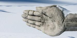 Carved wooden hand pointing direction over snowy lndscape