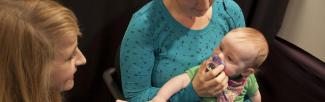 A researcher speaks with a mother and baby during a study.